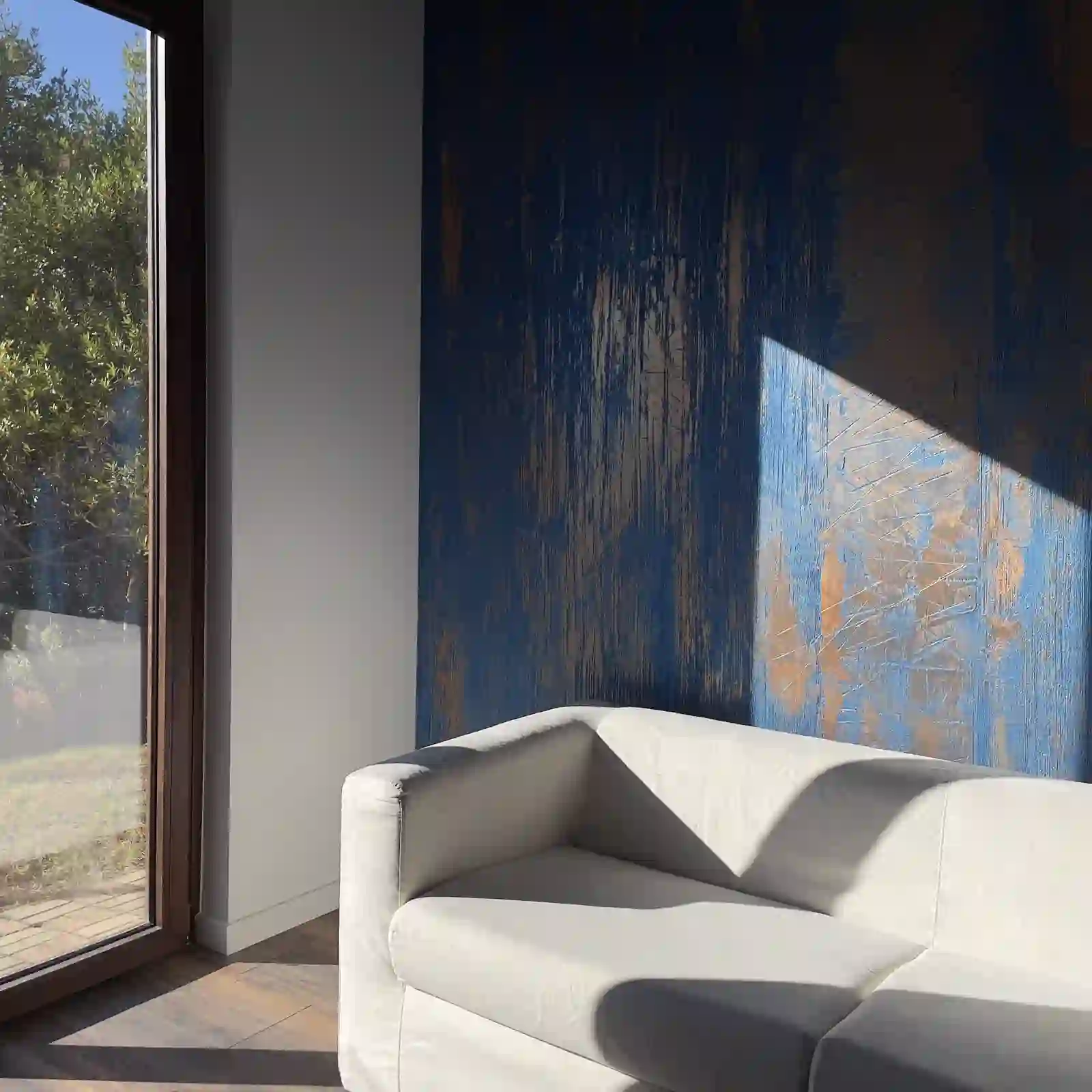 Poltrona chiara davanti a una parete blu con decori