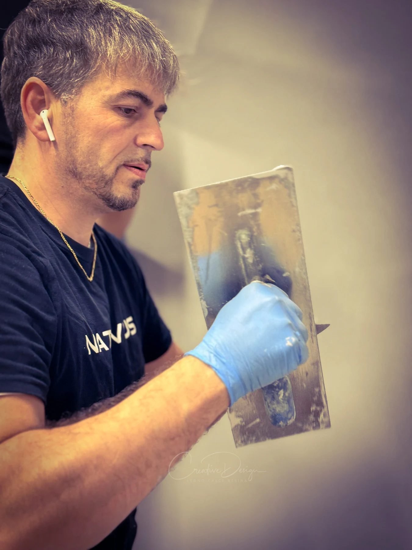Nicola Spulber con frattazzo e guanto blu durante un gesto di lavorazione
